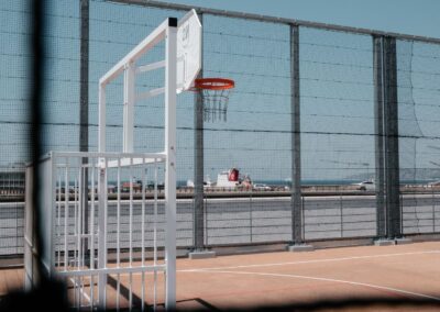 City stade du Collège Loyola à Marseille avec panier de basket et au loin les bateaux du port